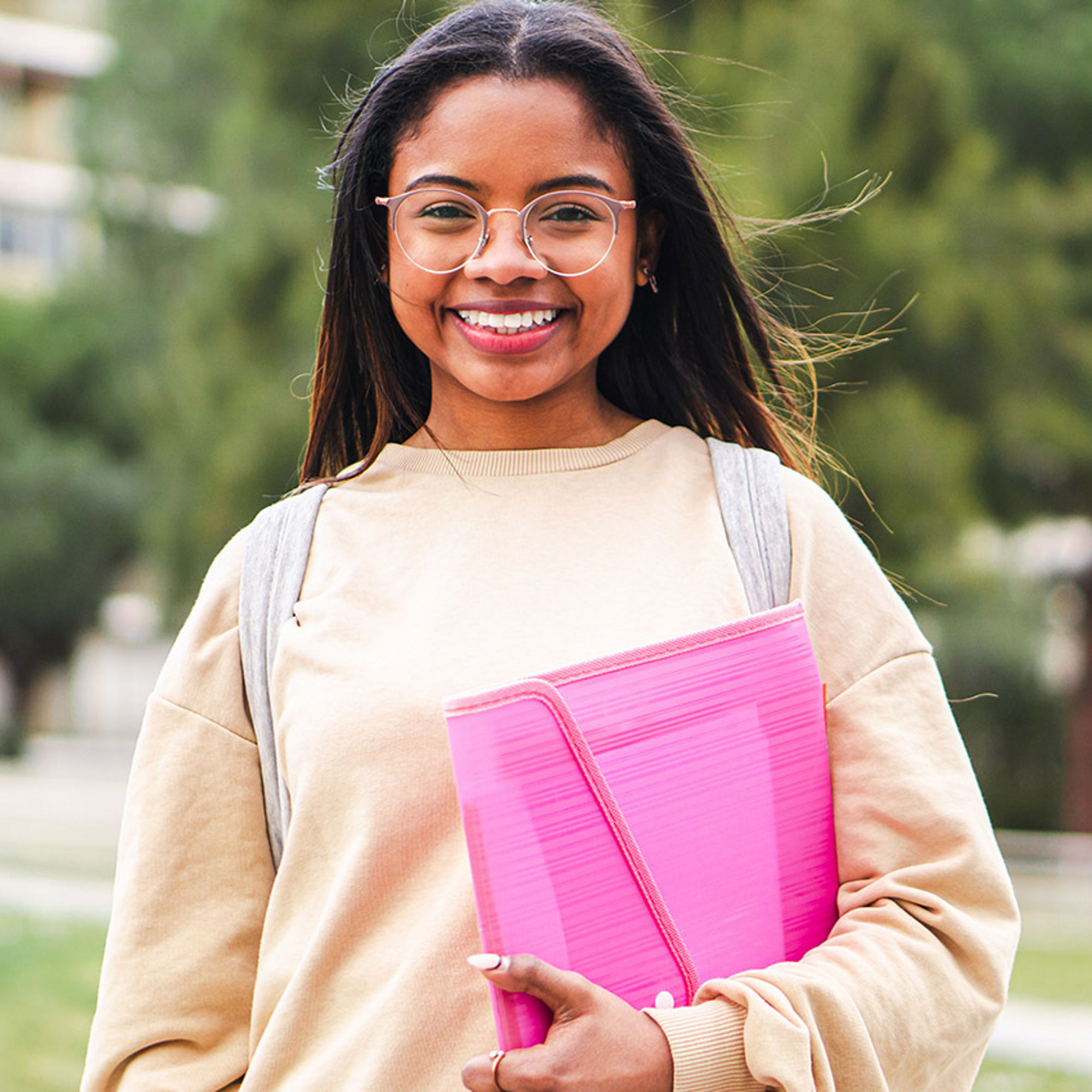 Young girl wearing backpack holding pink folder