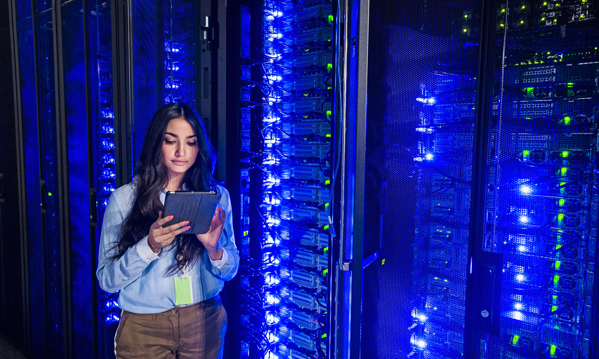 Mixed race technician using digital tablet in server room