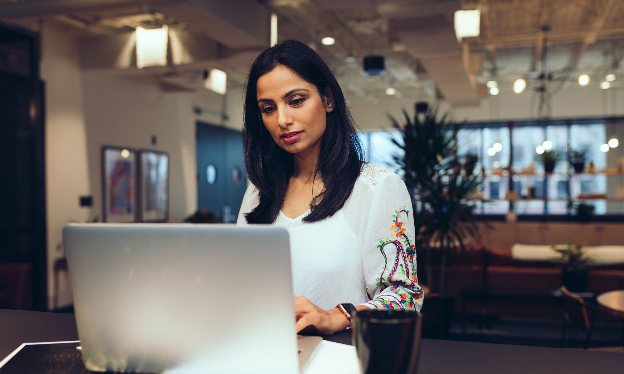 Millennial Eastern Indian woman in front of laptop in modern setting