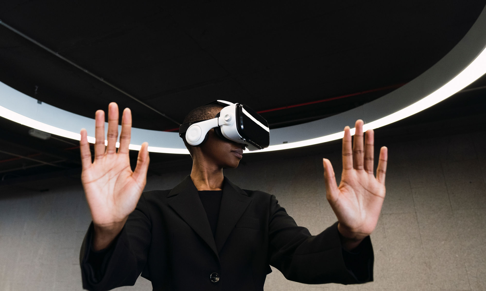 Young woman with VR glasses doing stop gesture in parking garage