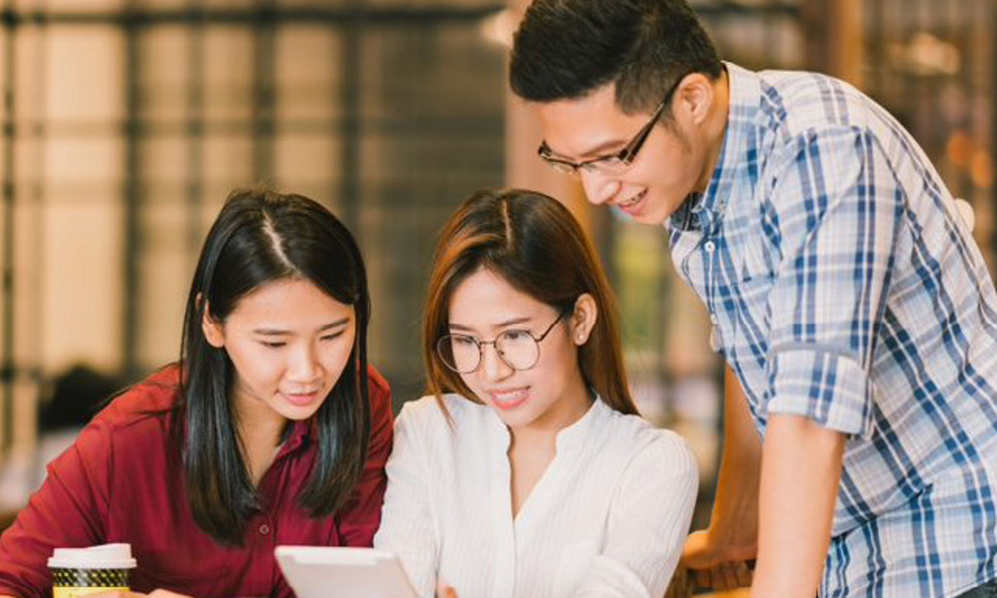 Three young people reading a table device