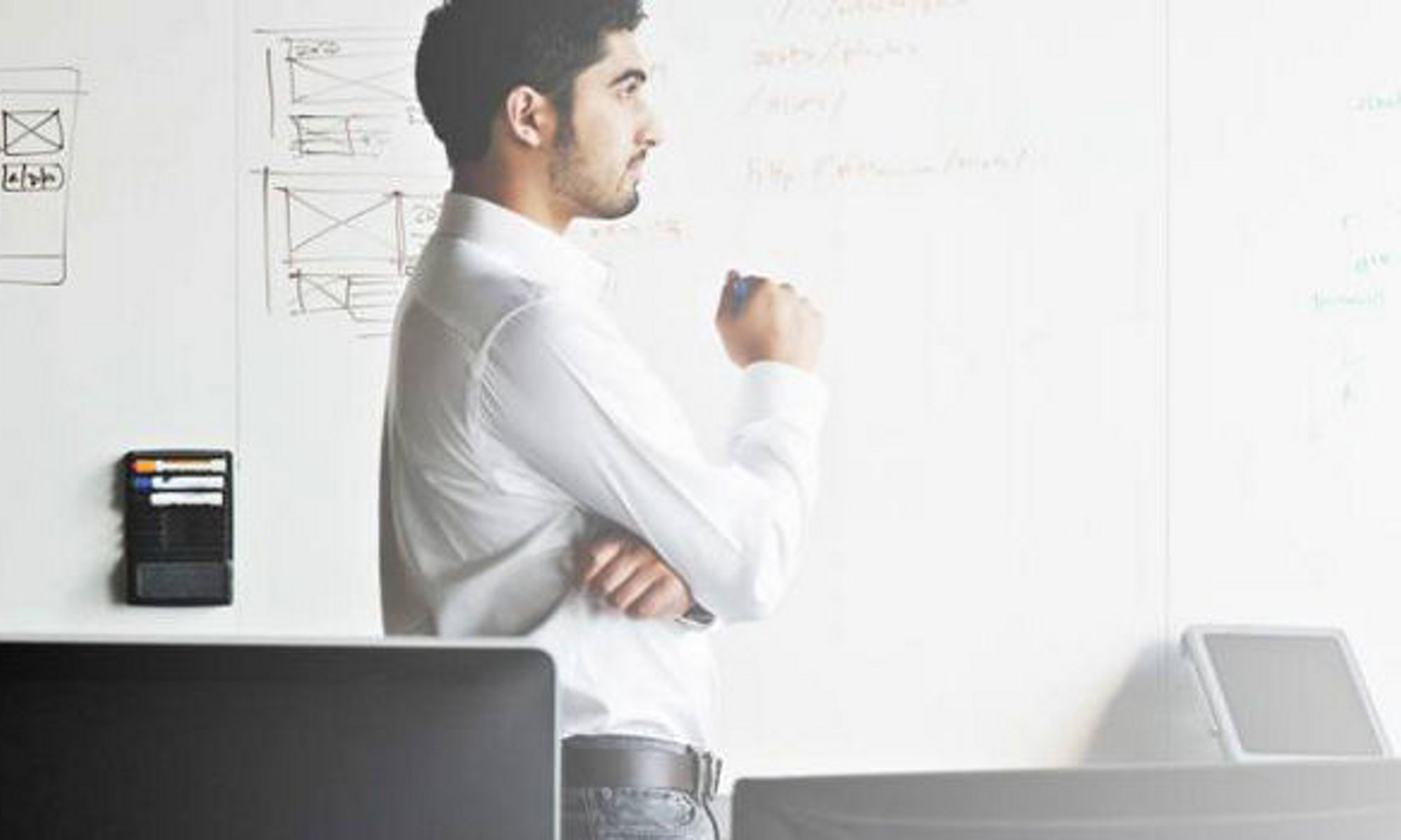 A man thinking in front of a white board