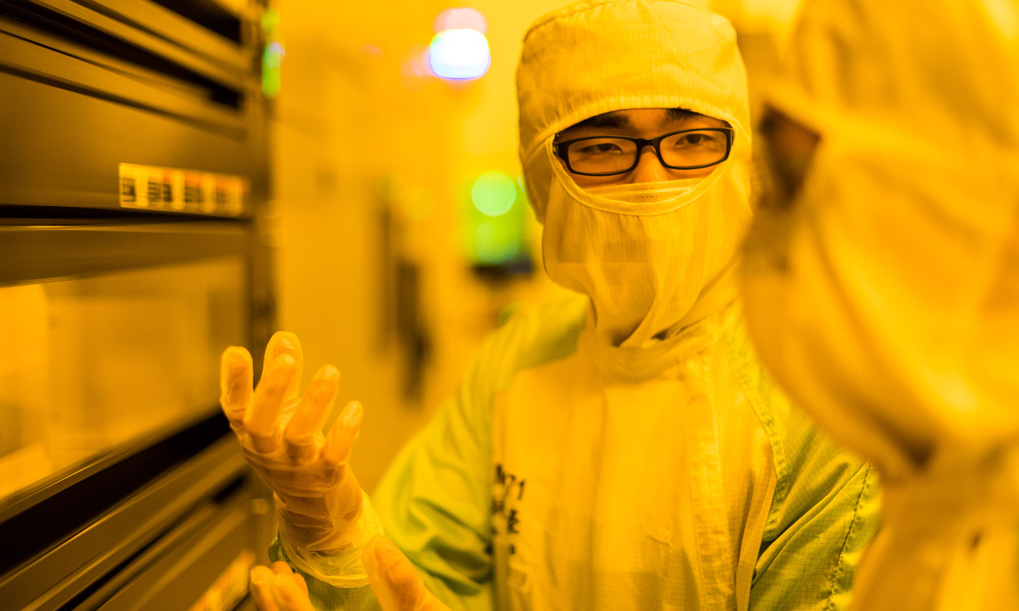 Bunny suited co-workers discussing  a project in a lab setting