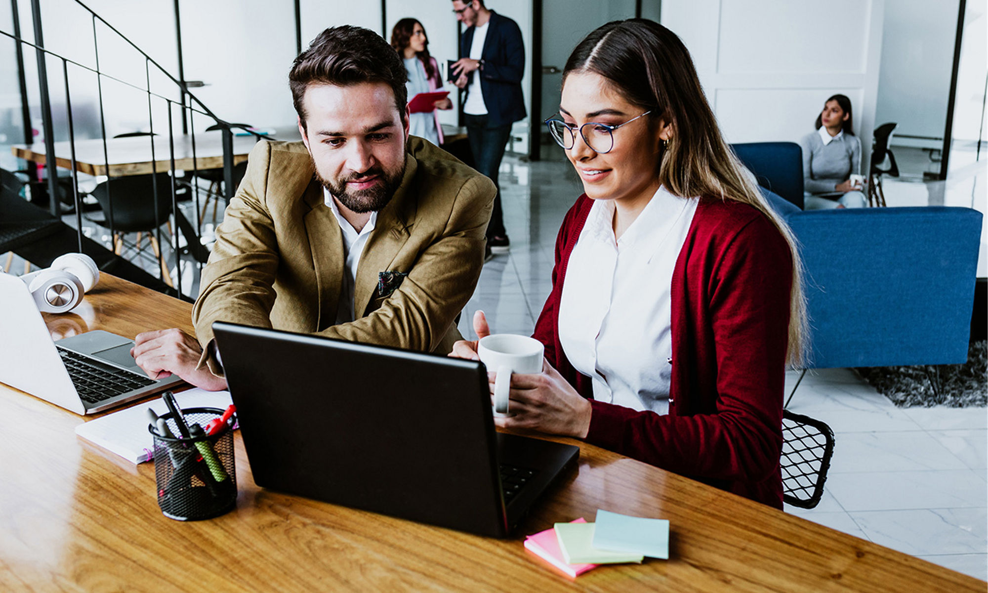 A business man and business woman sitting at a laptop together discussing what's on the screen